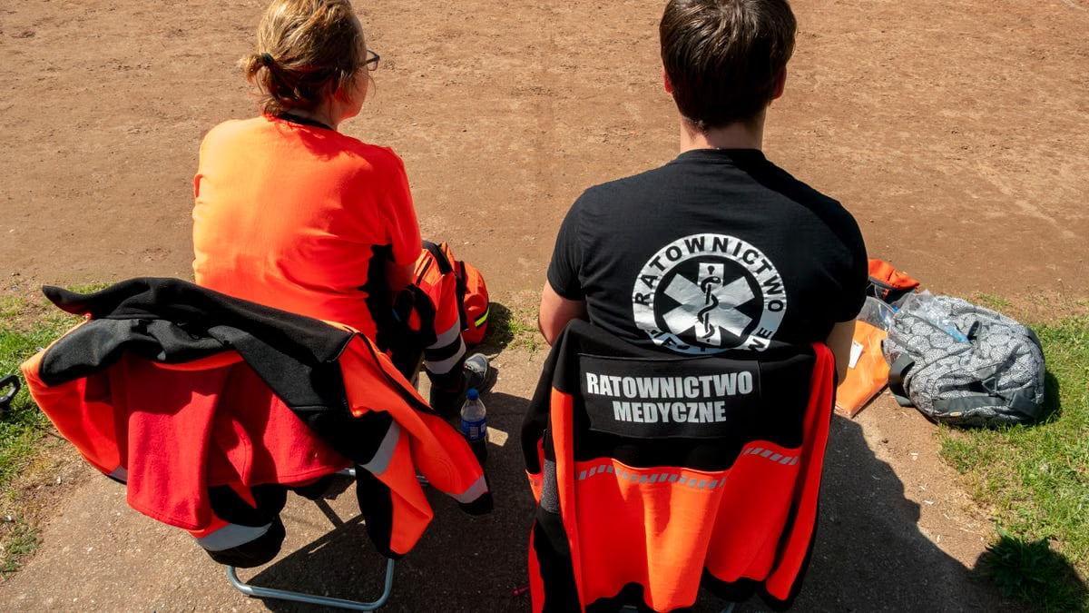 Two emergency medical technicians seated outdoors in Wrocław, Poland during a daytime event.